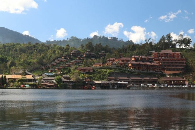 a large body of water next to a lush green hillside