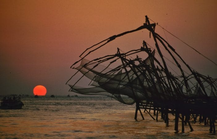 brown and white sail boat on sea shore during sunset