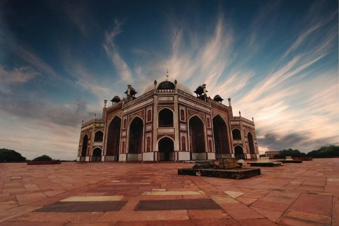 Stunning low angle view of Humayun's Tomb in Delhi against a dramatic sky at sunset.