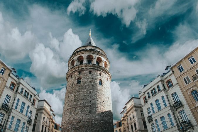 Captivating view of Galata Tower surrounded by historic architecture and dramatic clouds in Istanbul, Turkey.